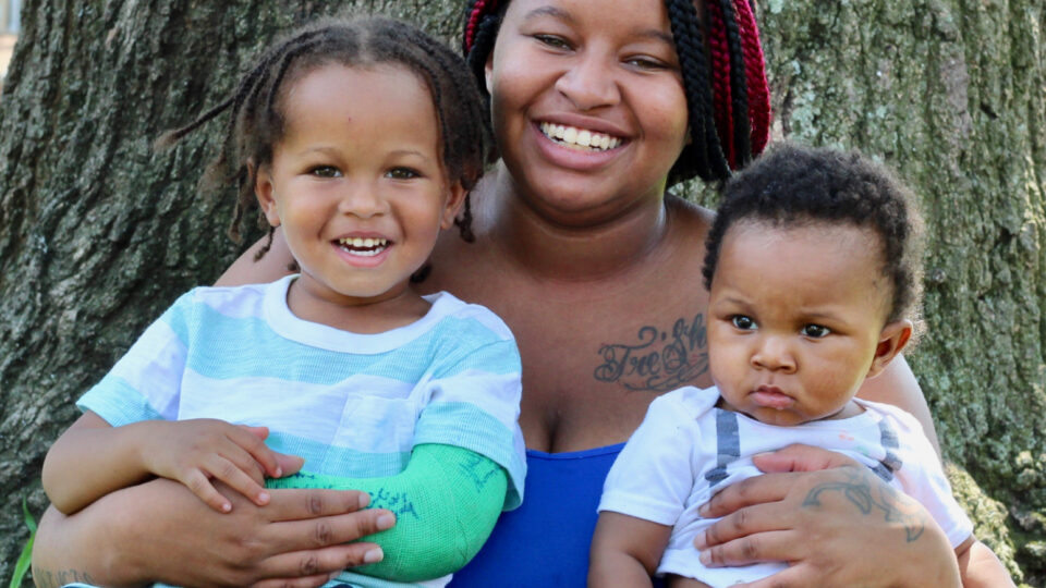 African American mother smiling outside with her two children