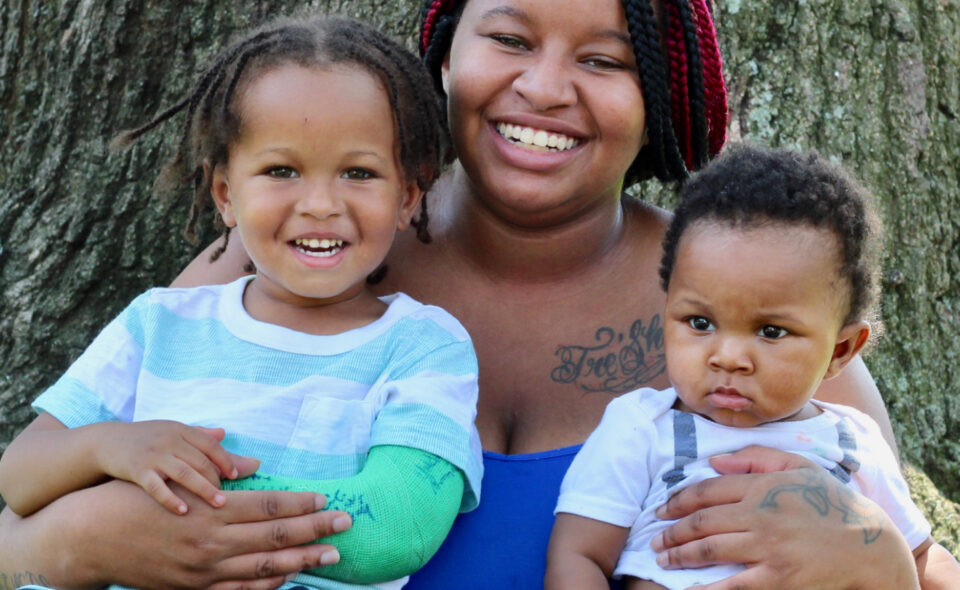 African American mother smiling outside with her two children